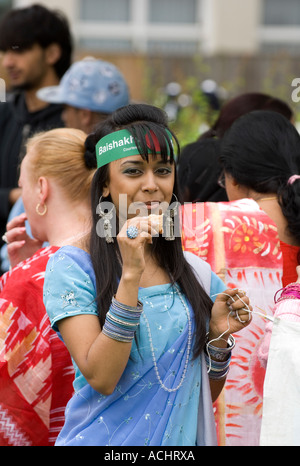 Young Asian woman wearing saree traditionnel, et un serre-tête Baishakhi Mela, manger un en-cas dans une foule Banque D'Images