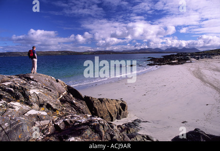 Randonneur à la recherche sur une plage de sable sur le rivage de Mannin Bay, Connemara, comté de Galway, Irlande. Banque D'Images