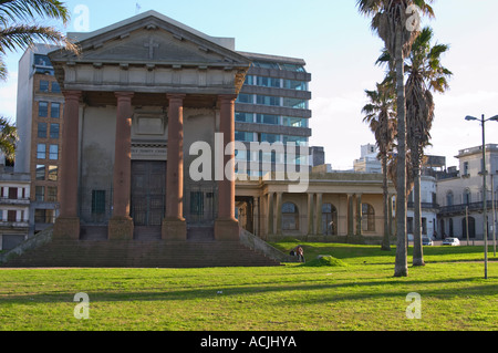 La Cathédrale Holy Trinity Anglican Church, Reconquista 522, Montevideo, dans la lumière du soleil. côté matin Pelouse à l'avant avec palmiers et de bâtiments modernes à l'arrière-plan. Un seul homme assis par l'église. Montevideo, Uruguay, Amérique du Sud Banque D'Images
