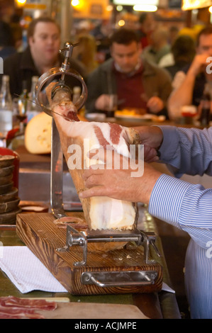 La barre de coupe homme minces tranches de jambon séché à sec d'un jambon sur un stand d'être servis au bar,, au restaurant El Palenque, l'espadon Espadon, dans le Mercado del Puerto, le marché dans le port Harbour Harbour où beaucoup de gens aller manger et magasiner le week-end, Montevideo, Uruguay, Amérique du Sud Banque D'Images