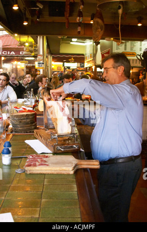 La barre de coupe homme minces tranches de jambon séché à sec d'un jambon sur un stand d'être servis au bar,, au restaurant El Palenque, l'espadon Espadon, dans le Mercado del Puerto, le marché dans le port Harbour Harbour où beaucoup de gens aller manger et magasiner le week-end, Montevideo, Uruguay, Amérique du Sud Banque D'Images