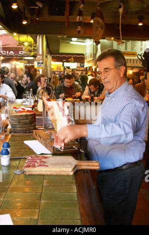 La barre de coupe homme minces tranches de jambon séché à sec d'un jambon sur un stand d'être servis au bar,, au restaurant El Palenque, l'espadon Espadon, dans le Mercado del Puerto, le marché dans le port Harbour Harbour où beaucoup de gens aller manger et magasiner le week-end, Montevideo, Uruguay, Amérique du Sud Banque D'Images