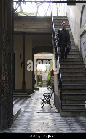 Intérieur d'une boutique d'antiquités dans le quartier San Telmo autour de la Plaza Dorrego Square, vue par une porte ouverte à la cour avec un escalier avec un homme qui marche et un banc de parc et plus d'escaliers à l'arrière-plan, soleil de derrière l'homme en lui donnant une silhouette look Calle Defensa Defence street Buenos Aires Argentine, Amérique du Sud Banque D'Images