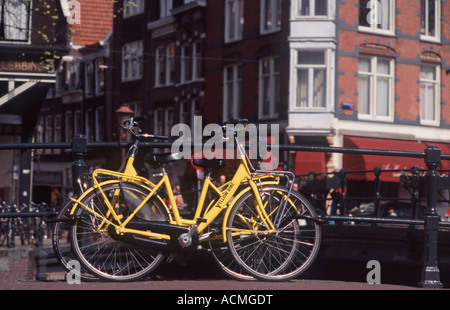 Deux bicyclettes jaune vif garé contre pont-canal, balustrades Spiegelgracht, Amsterdam, Pays-Bas Banque D'Images