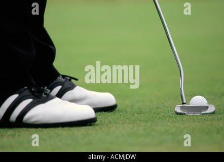 Un gros plan d'une des chaussures de golf putter et la balle sur un terrain de golf en été Banque D'Images