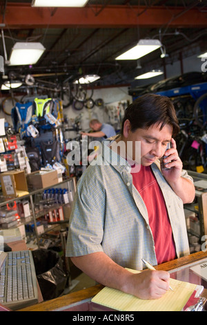 Propriétaire de magasin de bicyclettes hispanique à parler au téléphone Banque D'Images