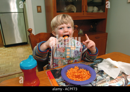 Enfant prenant une énorme bouchée de spaghetti nourriture humour enfant Banque D'Images
