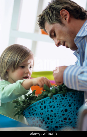 Père et fils examinant les fines herbes dans la cuisine Banque D'Images