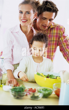 Parents fille (6-7) preparing salad Banque D'Images