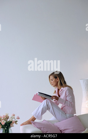 Young woman reading magazine, side view Banque D'Images