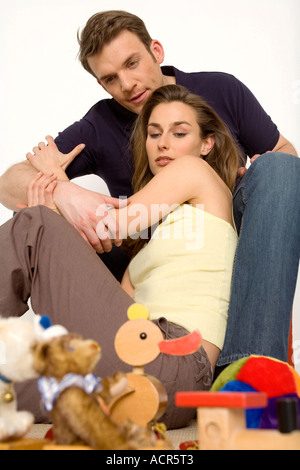 Jeune couple assis sur le plancher avec des jouets, close-up Banque D'Images