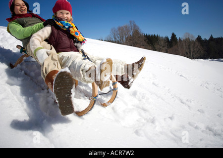 L'Autriche, les filles (6-17) de la luge sur la pente couverte de neige, smiling, low angle view Banque D'Images