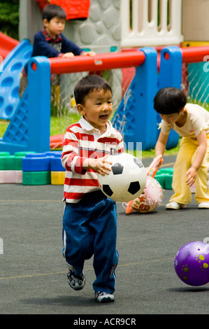 Boy Running with Ball Garderie Préscolaire Haut de Shanghai Chine Banque D'Images