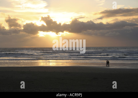 Marcher le long de Cannon Beach sur la côte de l'Oregon au coucher du soleil. Banque D'Images