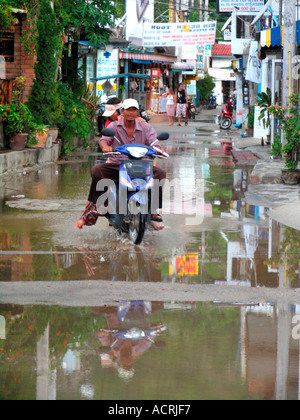 Moto sur la rue inondée après une averse Ko Pha Ngan island Thaïlande Banque D'Images