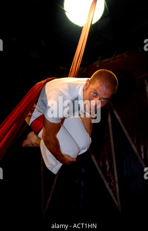 Artiste de cirque acrobat enchevêtré dans rideaux rouge Banque D'Images