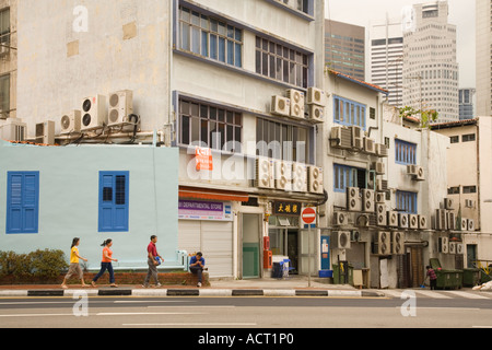 Trois personnes passent à côté d'un Singapour Retour rue pleine de climatiseurs Banque D'Images