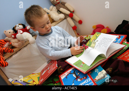 Tout-petits jeunes à la recherche de livres dans le lit Banque D'Images