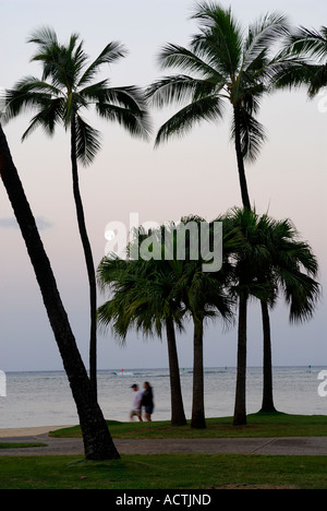 Couple on tôt le matin, se promener sous le clair de lune sur une plage de Waikiki Oahu Hawaii Banque D'Images
