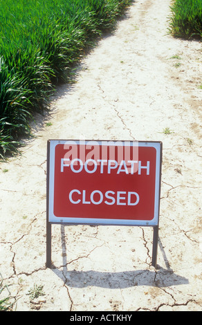 Le rouge et le blanc des panneau routier sur le chemin de la boue crayeuse séché dans le champ de blé de printemps indiquant sentier fermé Banque D'Images