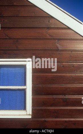 Détail de brown woodstained beach hut avec garniture blanc et bleu utilisé comme serviette à rideau de fenêtre, sous ciel bleu profond Banque D'Images