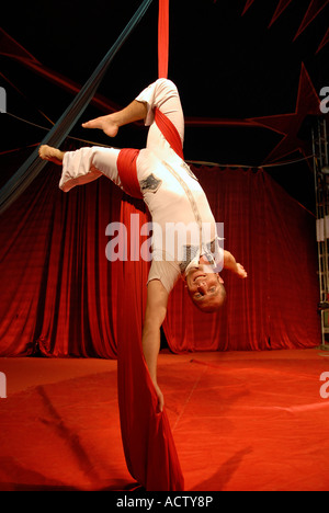 Artiste de cirque acrobat enchevêtré dans rideaux rouge Banque D'Images