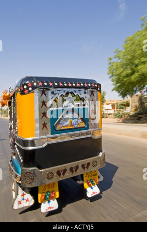 Un décoré de jaune et noir auto rickshaw (tuk tuk) provenant d'un autre avec une vitesse d'obturation lente pour le motion blur. Banque D'Images