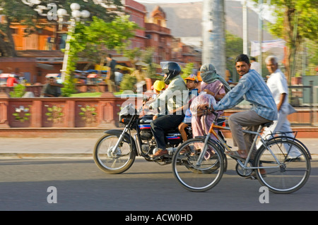 Une famille indienne de 4 sur une moto et l'homme à vélo dans une scène de rue typique à Jaipur avec le panoramique de flou. Banque D'Images