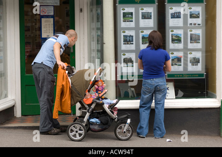 Jeune couple avec enfant en poussette à la maison à la fenêtre propriété détails estate agents Llandeilo Carmarthenshire West Wales UK Banque D'Images