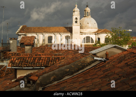 Sur les toits de Venise avec bardeaux en terre cuite et les cheminées et les antennes et le toit dome et clocher d'une église Banque D'Images
