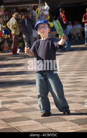 Editorial N'utilisez que le modèle ne libération petit garçon en jeans casquette lunettes gesticulant avec bouteille de soda comme si directeur musical Banque D'Images