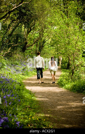 Jeune couple strolling au soleil dans le Parc Nature Penglais Ceredigion Pays de Galles Aberystwyth Park sur une après-midi d'été printemps Banque D'Images
