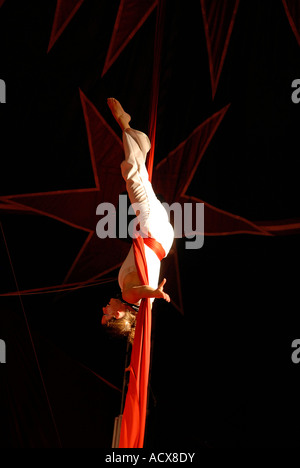 Artiste de cirque acrobat enchevêtré dans rideaux rouge Banque D'Images