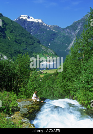 Woman next to stream tomber dans le Geirangerfjord avec navire à passagers Banque D'Images