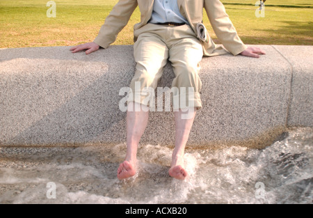 Le refroidissement de l'homme ses pieds dans le Princess Diana Memorial Fountain. Hyde Park. Londres. L'Angleterre. Banque D'Images