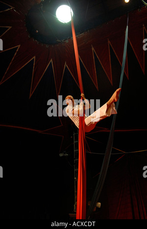 Artiste de cirque acrobat enchevêtré dans rideaux rouge Banque D'Images