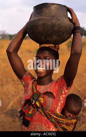 Femme au Mozambique avec de l'eau pot sur sa tête et bébé au dos Banque D'Images