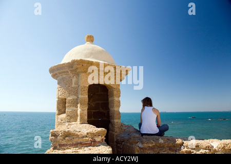 Femme assise sur un mur à bord de Castillo de Santa Catalina (château de Santa Catalina), Cadiz, Espagne Banque D'Images