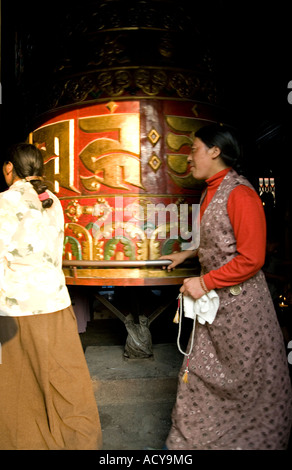 Femme tibétaine la rotation d'un grand moulin à prières.Bodhnath Stupa.La vallée de Katmandou au Népal. Banque D'Images