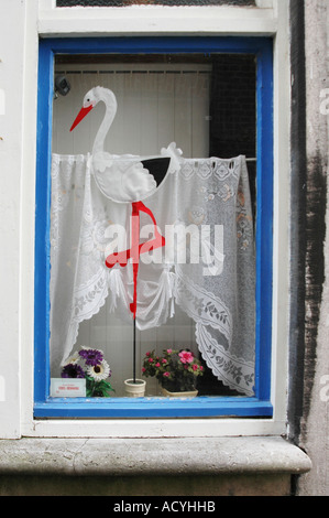 Afficher la fenêtre de cigogne debout dans un pot de fleurs représentant la naissance de bébé fille ou garçon Banque D'Images