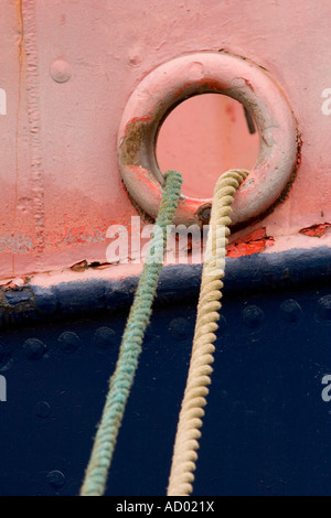 Des amarres en sortant d'un trou dans une coque de navires rouge et bleu Banque D'Images