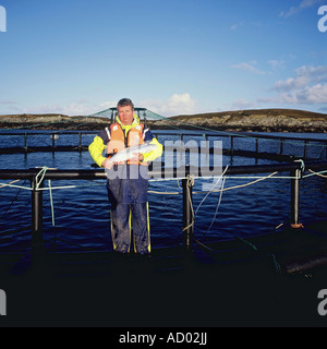 Angus Mcmillian appuie fièrement l'un de ses saumons d'organiquement capturé dans les eaux cristallines de la côte de Ni Banque D'Images