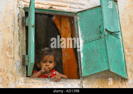 Portrait horizontal d'un beau petit Indian girl staring out d'une haute fenêtre. Banque D'Images