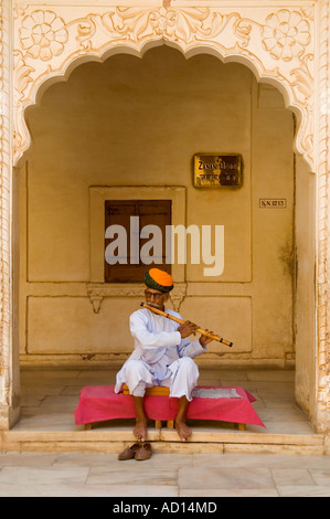 Portrait vertical d'un vieux musicien indien jouant une longue flûte en bois sous une arche décorative au Fort Mehrangarth. Banque D'Images