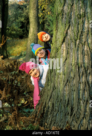Deux garçons et une fille se cacher derrière tree Banque D'Images