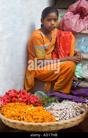 Portrait vertical d'une jeune Indienne vendant des guirlandes de fleurs aux couleurs vives à l'extérieur d'un temple Banque D'Images