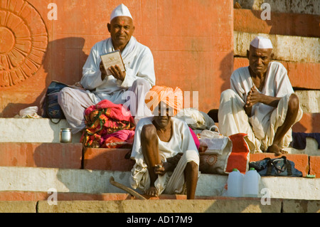 Close up horizontale de trois hommes âgés assis sur Kedar Ghat regarder le monde passer par Banque D'Images