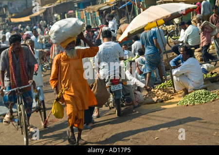 Grand angle horizontal d'un Indien typique occupé scènederue avec un homme portant un gros paquet sur sa tête, marchant le long de la route Banque D'Images