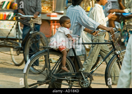 Portrait d'une petite horizontale jeune fille embrayer sur l'arrière d'un vélo comme son père le pousse à travers les rues buste. Banque D'Images