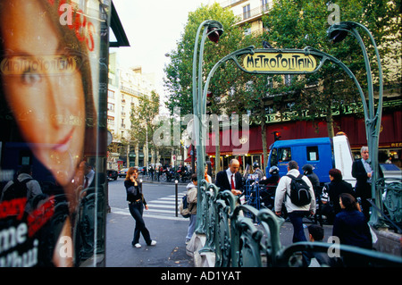 Femme parlant sur un téléphone en face d'une grande affiche publicitaire et l'Art Nouveau au métro Place de Clichy Paris, France Banque D'Images